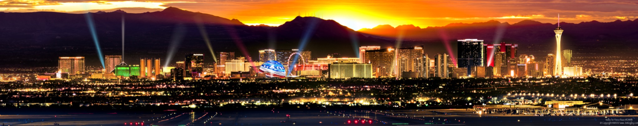 Panorama of the Las Vegas skyline beneath an orange sunset and mountain silhouettes.